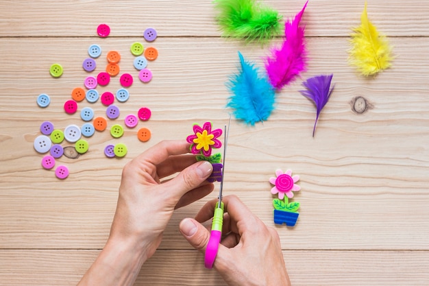 Close-up of a person's hand cutting flower sticker over the table