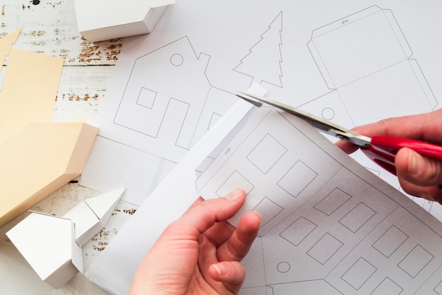 Free photo close-up of a person's hand cutting the white paper with scissor