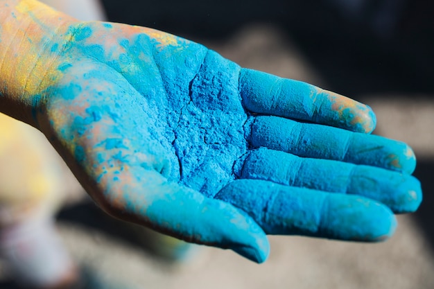 Close-up of a person's hand holding blue holi color