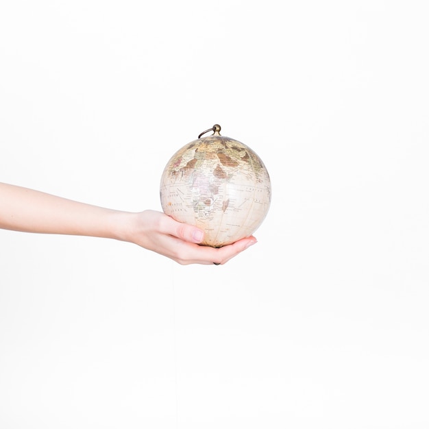 Free photo close-up of a person's hand holding globe pendulum on white background