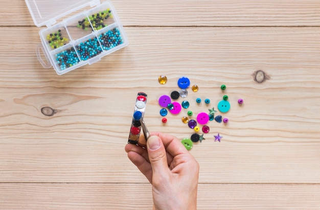 Close-up of person's hand sticking colorful beads on bracelet