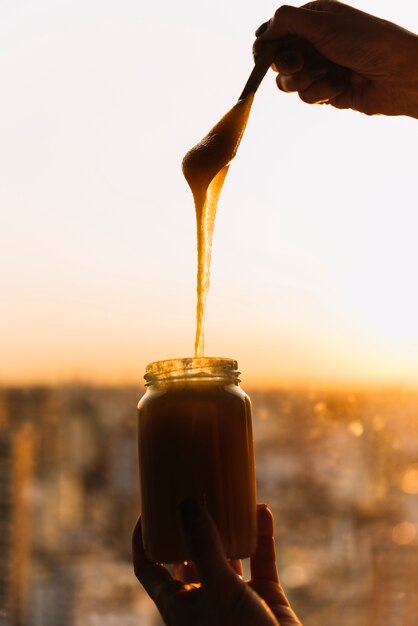 Close-up of person's hand with jar of lemon curd