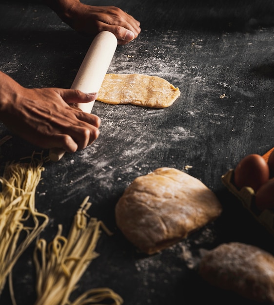 Free photo close-up person spreading dough on black table