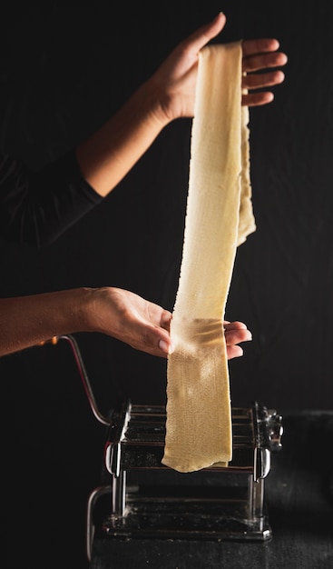 Free photo close-up person spreading pasta dough