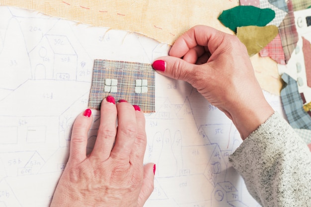 Close-up of a person sticking fabric patch on drawing paper over the desk