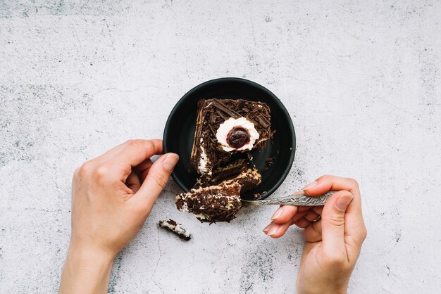 Close-up of a person taking chocolate cake with spoon on grunge background