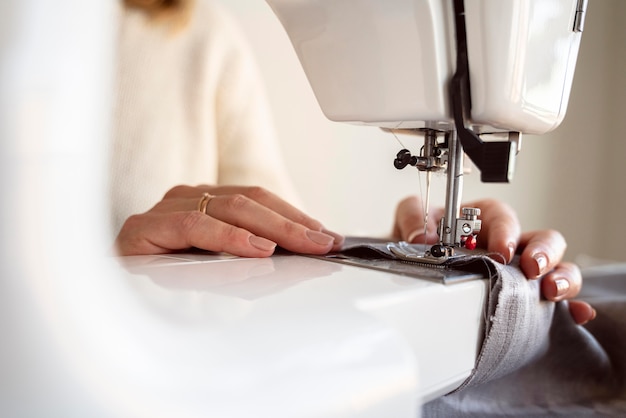 Close-up person using sewing machine