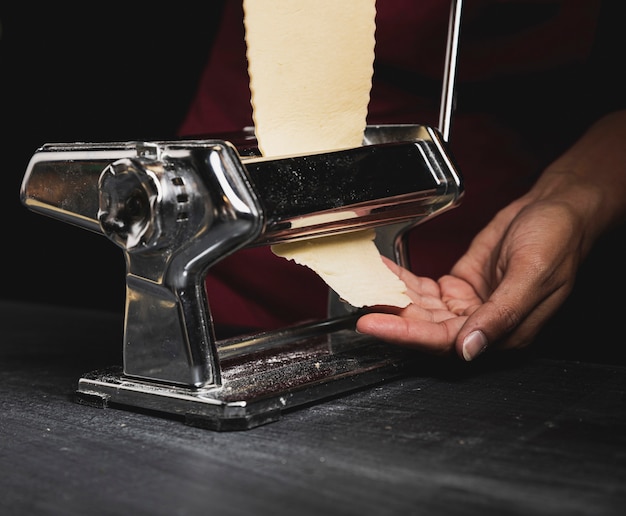 Close-up person with machine for pasta