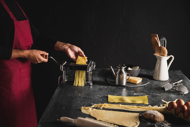 Close-up person with red apron and pasta machine