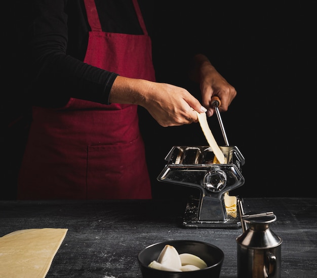 Close-up person with red apron and pastry machine