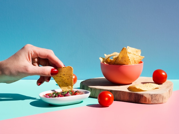 Free photo close-up person with tortilla chips and sauce