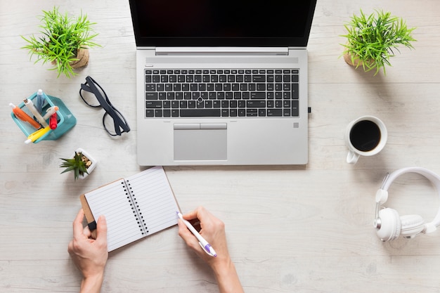 Free photo close-up of a person writing in the diary on wooden office desk