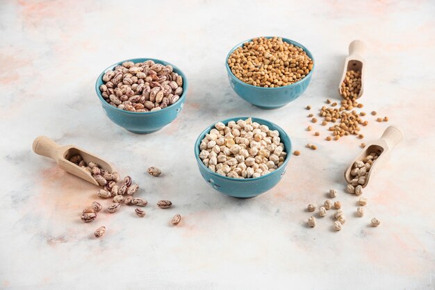 Close up photo of Bean, pasta and chickpea in bowls over white surface.