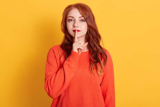 Close up photo beautiful lady with red pomade, long red hairstyle, keeping index finger near mouth