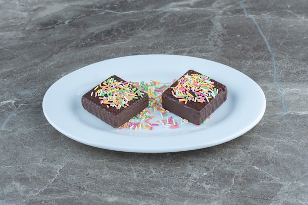 Close up photo of chocolate wafers on white ceramic plate.