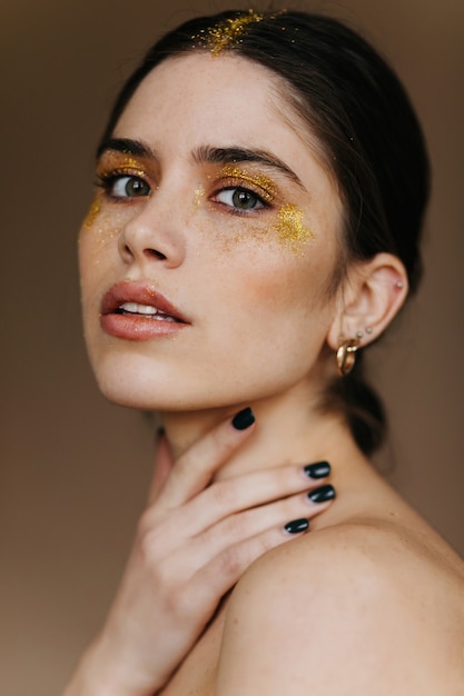 Free Photo close-up photo of curious young lady in golden jewerly.  glamorous brunette woman in earrings.