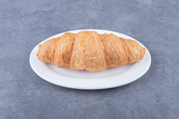 Close up photo of Fresh French croissant on white plate.