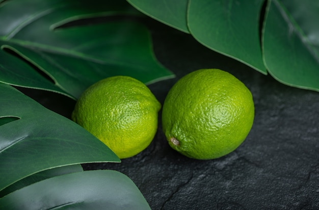 Free photo close up photo of fresh lime with green leaves on black background