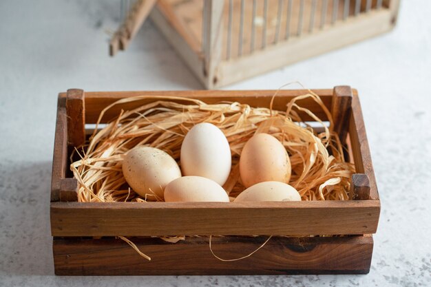 Free photo close up photo of fresh organic chicken eggs on straw in wooden box.