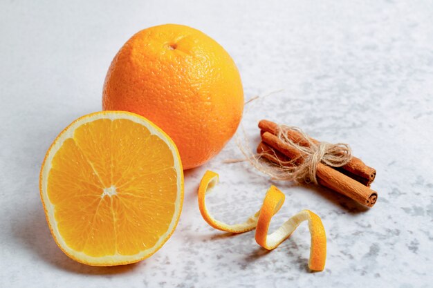 Close up photo of half cut or whole fresh orange with cinnamon. 