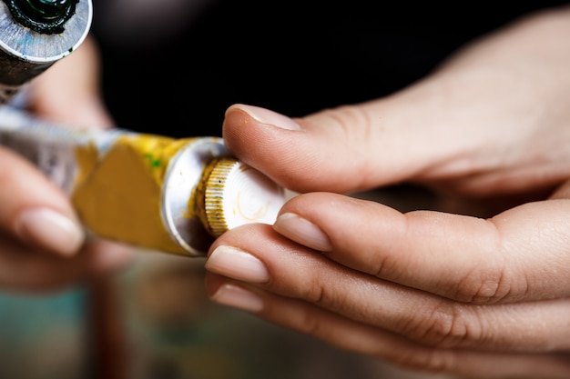 Free photo close up photo of hands closing yellow oil paint