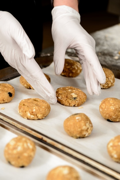 Close-up photo of hands puting tasty cookies on a baking tray