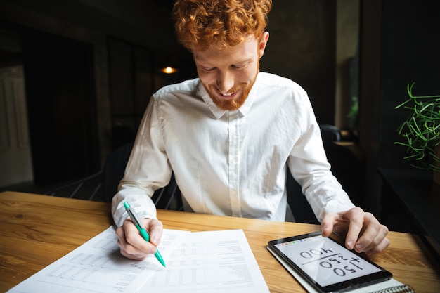 Free photo close-up photo of handsome readhead bearded man in white shirt, smiling while working at home