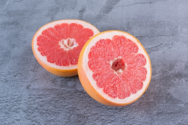 Close up photo of juicy grapefruit slices on grey.