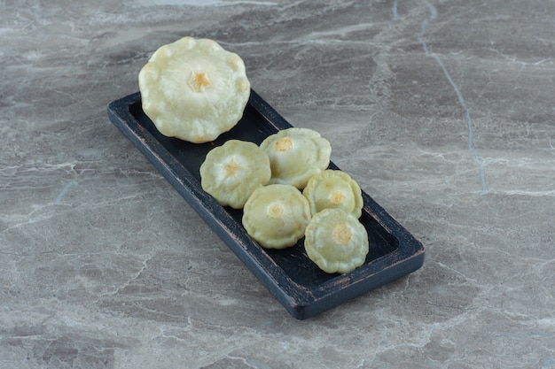 Free photo close up photo of pickle green patty pan squash on black plate.