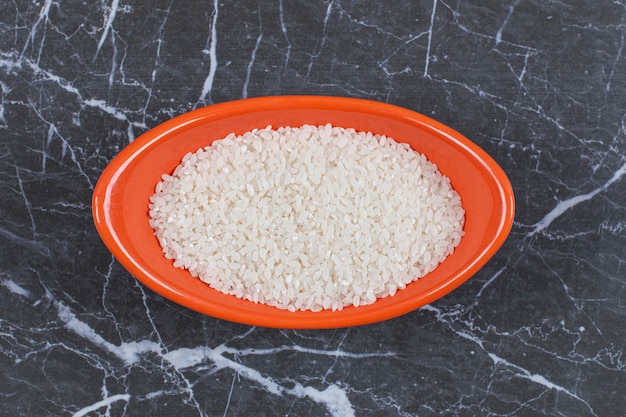 Free photo close up photo of raw uncooked rice in orange bowl.