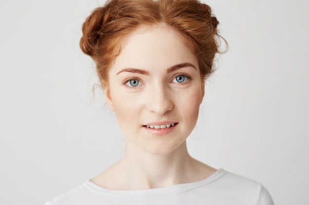 Close up photo of young beautiful redhead girl with buns smiling .