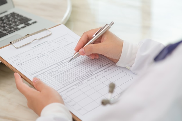 Close-up of physician's hands with clipboard and pen