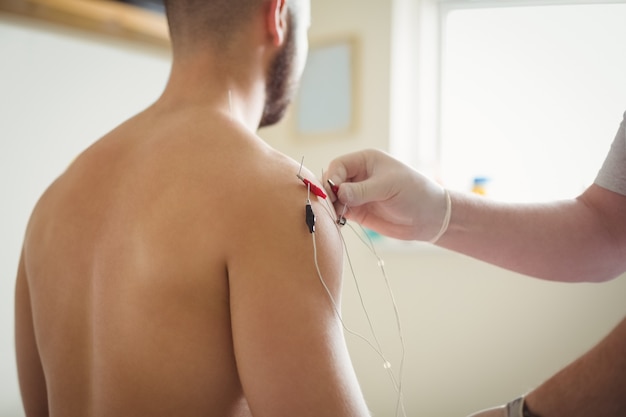 Free Photo close-up of physiotherapist inserting needles on patient