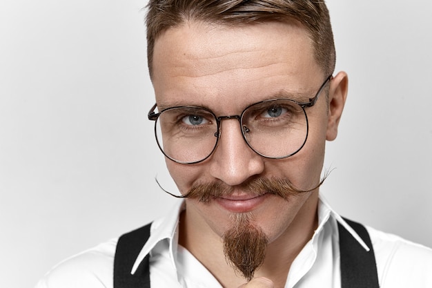 Close up picture of attractive positive banker with handlebar mustache, goatee beard and smart blue eyes