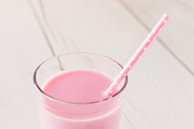 Close-up of pink milkshake in glass with straw