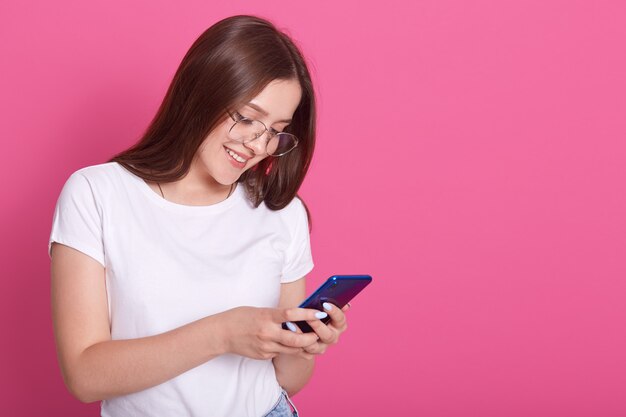 Close up portrait of adorable woman typing message to her friends or husbaund. Young female holding mobile phone