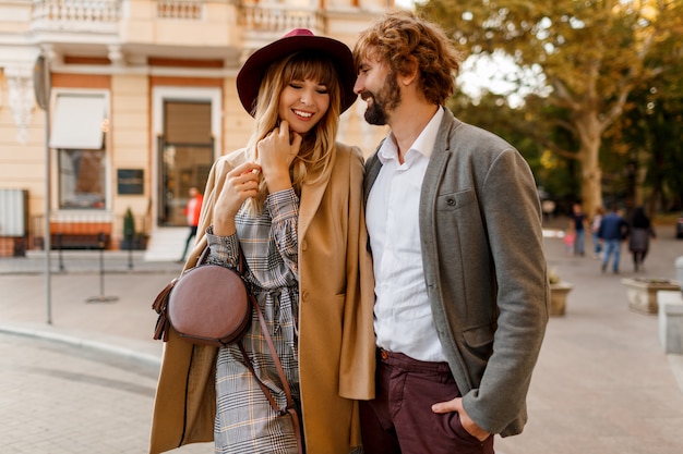 Free photo close up portrait of amazing stylish couple in love spending romantic holidays in european city. pretty blond woman in hat and casual dress smiling and looking on her handsome man with beard.