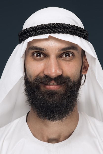 Free photo close up portrait of arabian saudi sheikh. young male model standing and smiling, looks happy.