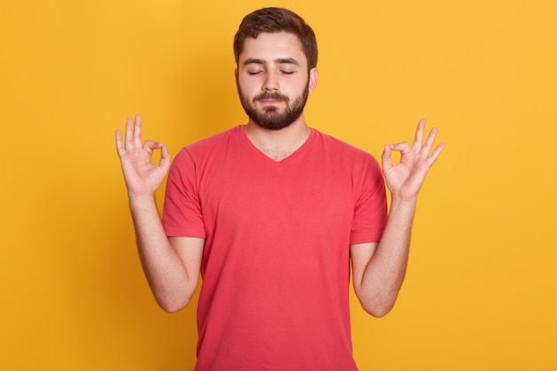 Free photo close up portrait of attractive man dresses red casual t shirt gesturing ok sign with closed eyes