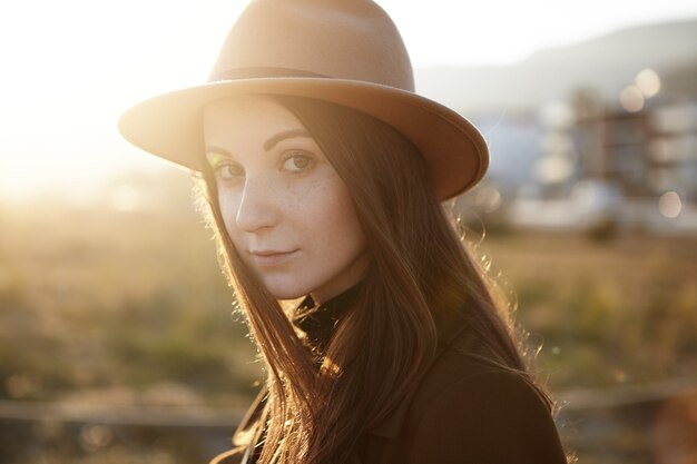 Close up portrait of attractive young European female wearing trendy hat and coat