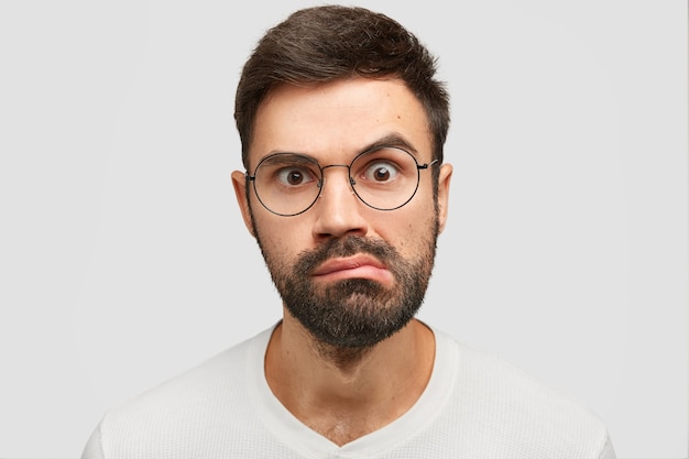 Close up portrait of attractive young man with dark stubble, looks surprisingly