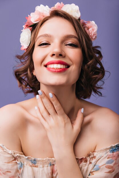 Close-up portrait of blithesome woman with trendy manicure and makeup. smiling lovable girl in flower wreath.