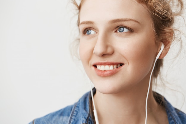 Free Photo close-up portrait of charming european ginger girl looking aside with confident and kind expression while listening music