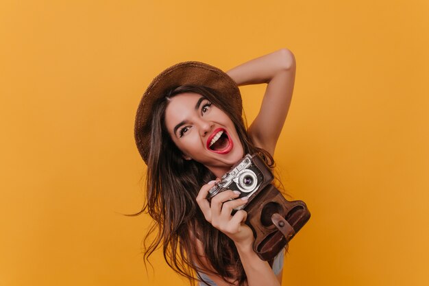 Close-up portrait of charming female photographer laughing on colorful space