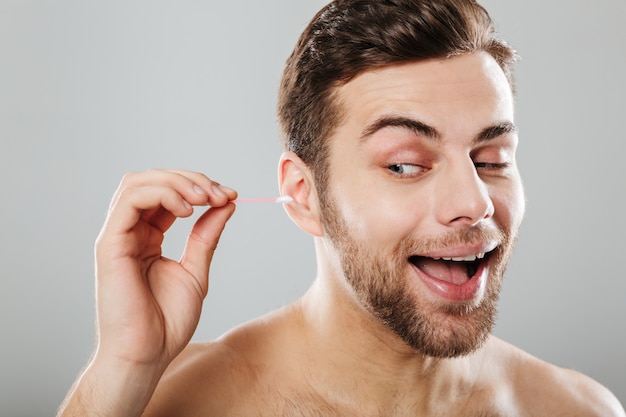 Close up portrait of a cheery man cleaning his ears