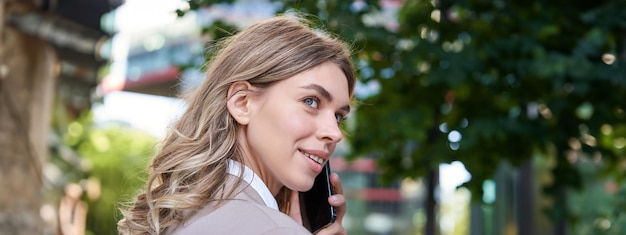 Free photo close up portrait of corporate woman calling on mobile phone walking on street with work documents