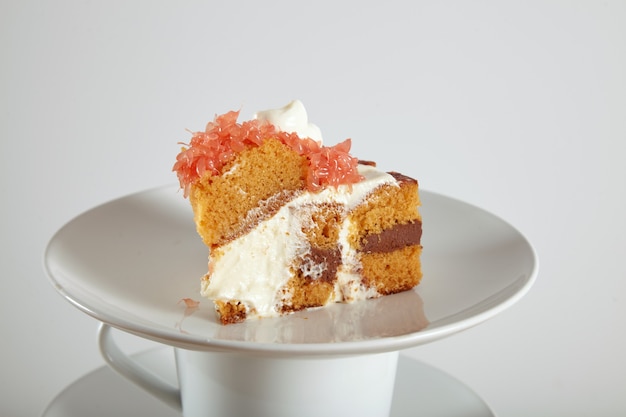 Free photo close up portrait of a delicious sponge cake with chocolate filling, cream and grapefruit on saucers and cups