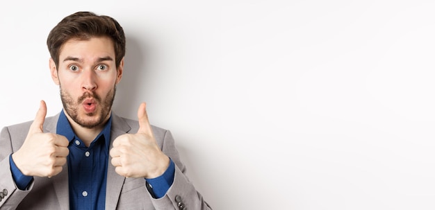 Free photo close up portrait of excited guy in suit say wow showing thumbs up with amazed face checking out awe