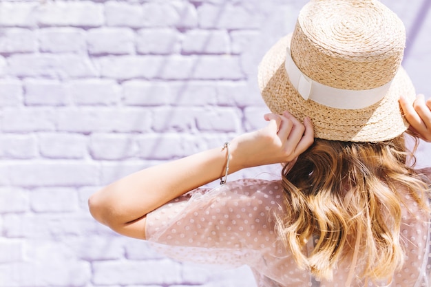 Free photo close-up portrait of fair-haired girl with lightly tanned skin posing with hands up in front of white wall