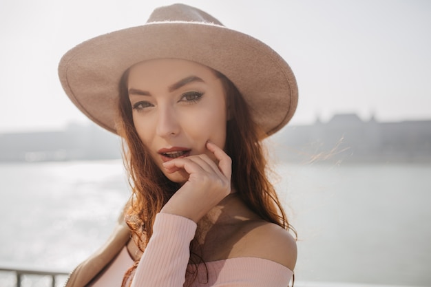 Close-up portrait of fascinating ginger woman standing on sea wall